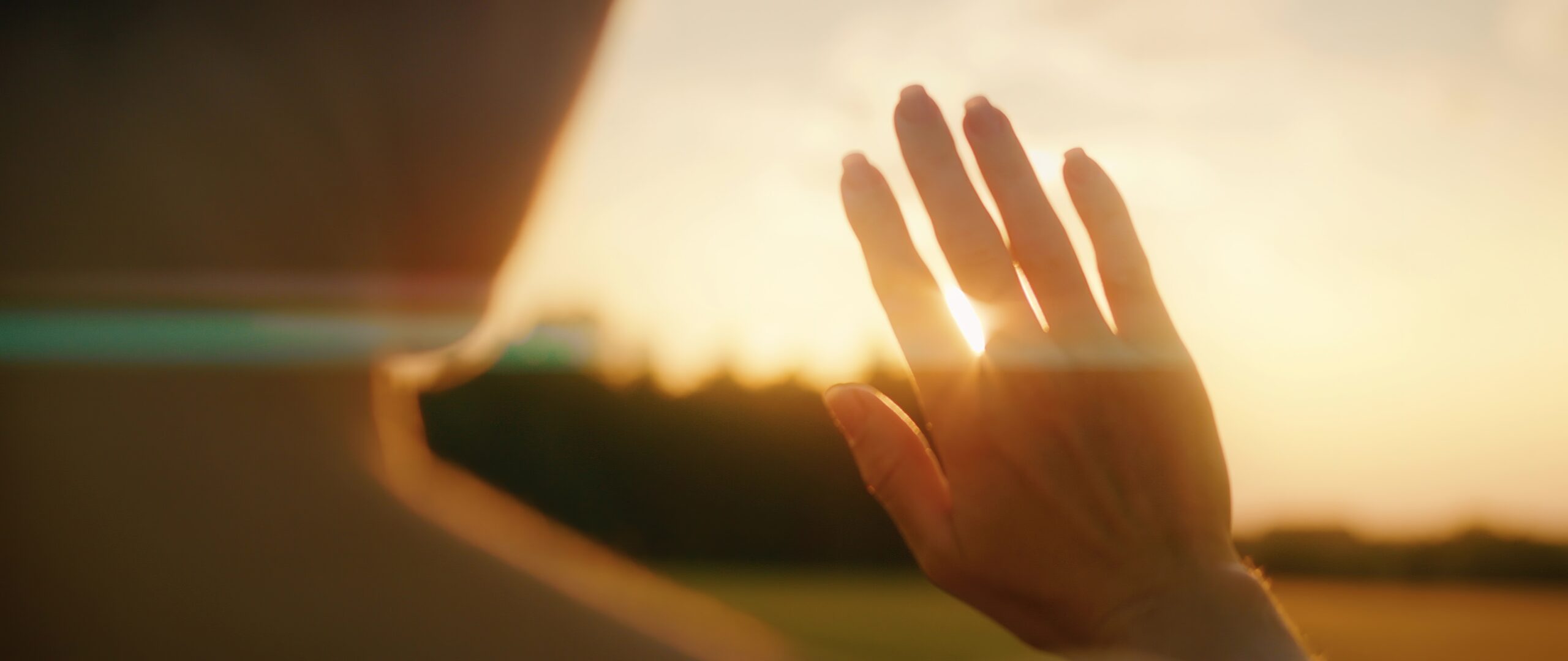 Woman catching solar energy with her hands. Warm rays of the setting sun in summer. Girl touches the light.