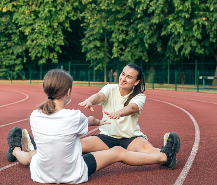Mother and daughter go in for sports outdoors, caucasian woman and little girl are engaged in fitness at the stadium.